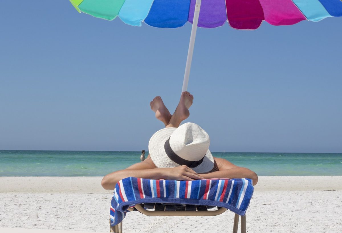 person laying on beach in a beach chair, ocean in background