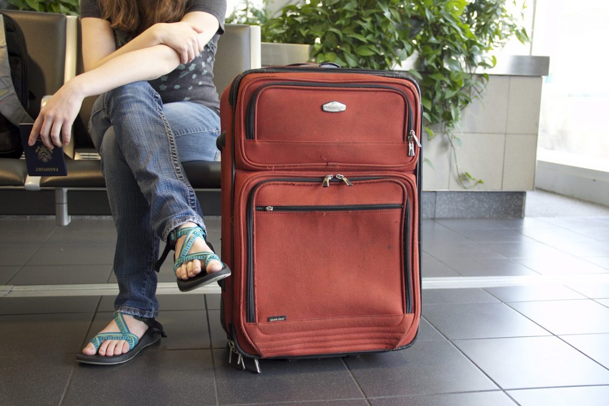 woman sitting beside suitcase