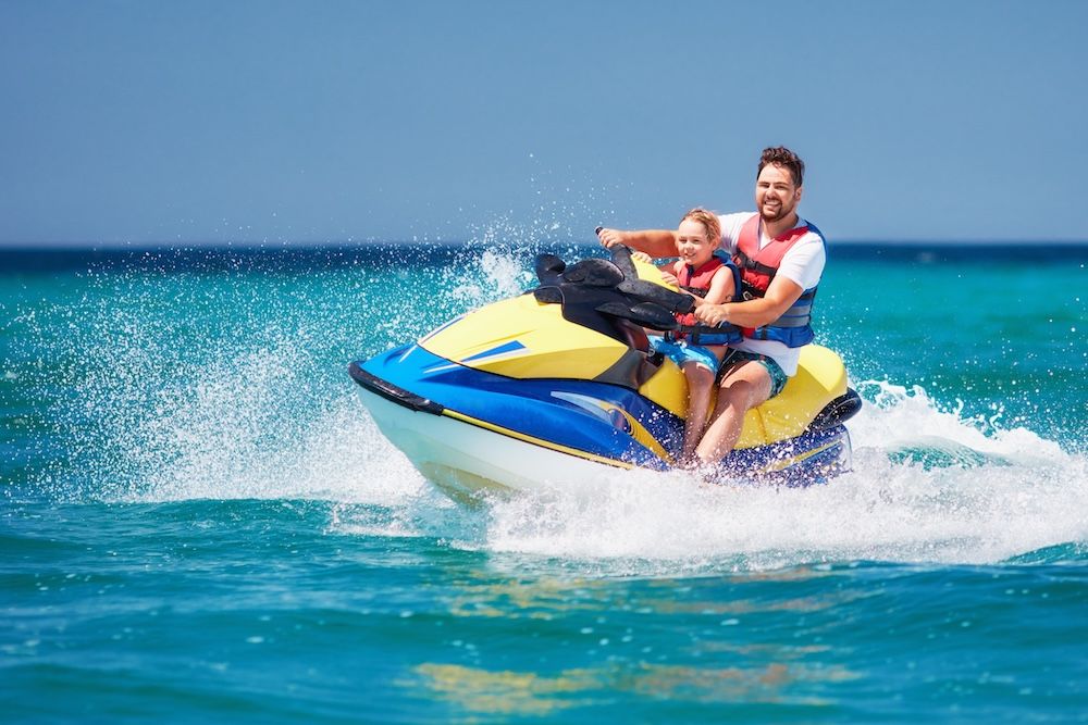 man and child rising a jet ski
